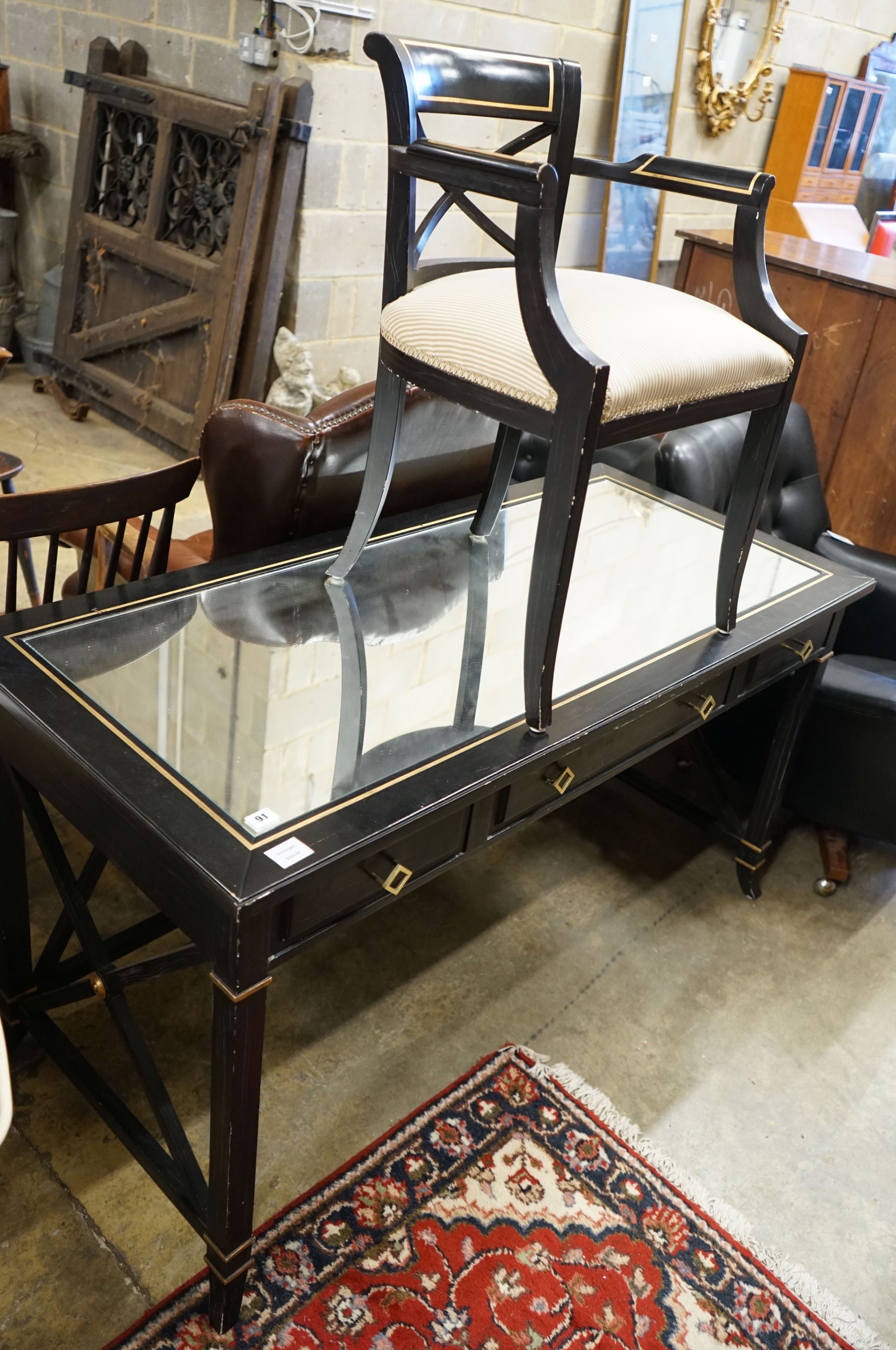 A painted mirrored three drawer ebonised writing table, length 140cm, depth 64cm, height 76cm together with a matching tub framed elbow chair